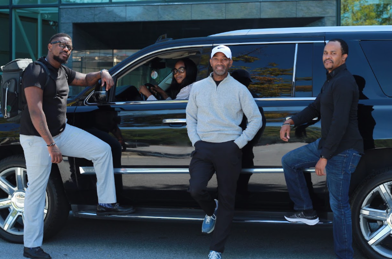 Riders posing beside the black RealChill Cadillac Escalade